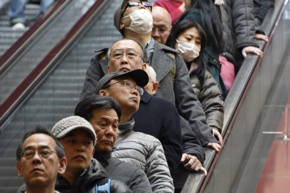 People stand in an escalator near Tokyo. Japan's population has dropped 0.7 per cent in five years. Photo: EPA