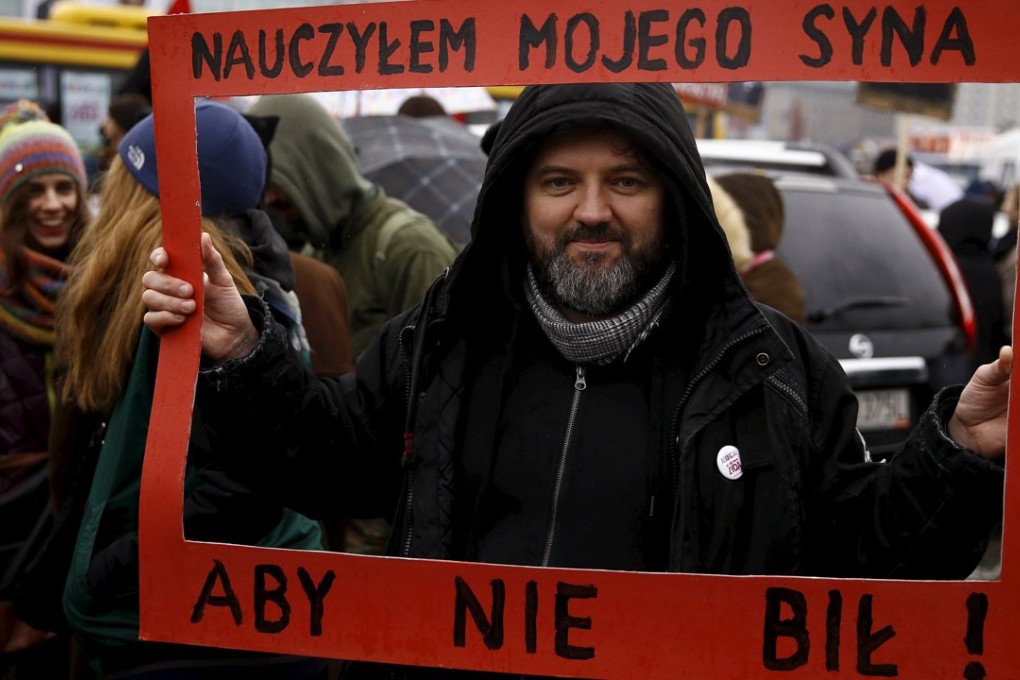 A man holds a placard which reads “I have taught my son to not beat” during an annual march in Poland ahead of International Women’s Day. Photo: Reuters