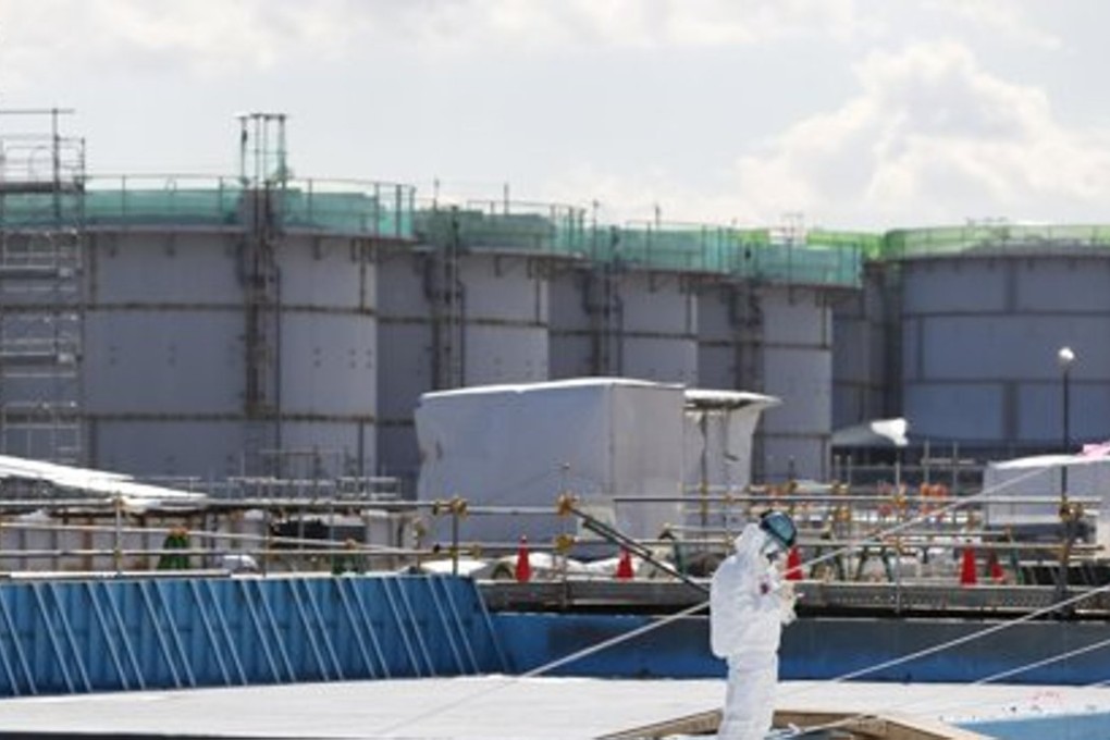 A worker, wearing protective suits and masks, takes notes the storage tanks for radioactive water at the tsunami-crippled Fukushima Daiichi nuclear power plant. Photo: Reuters