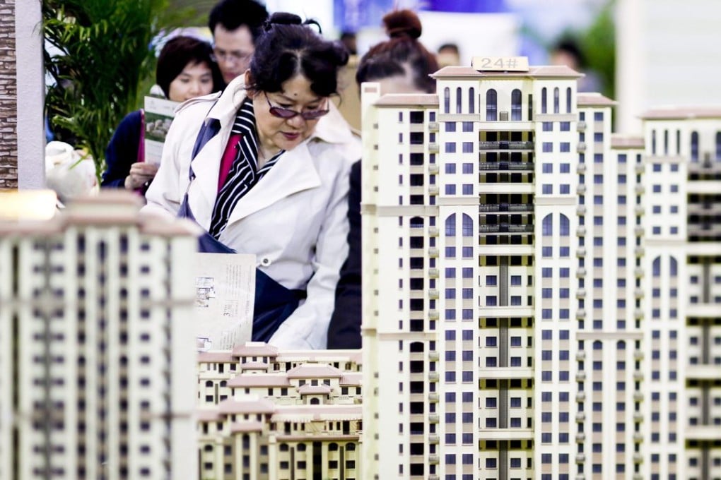 People looking at models of new residential developments for sale at a real estate fair in Beijing, among the Chinese cities where property prices have risen rapidly. Photo: EPA