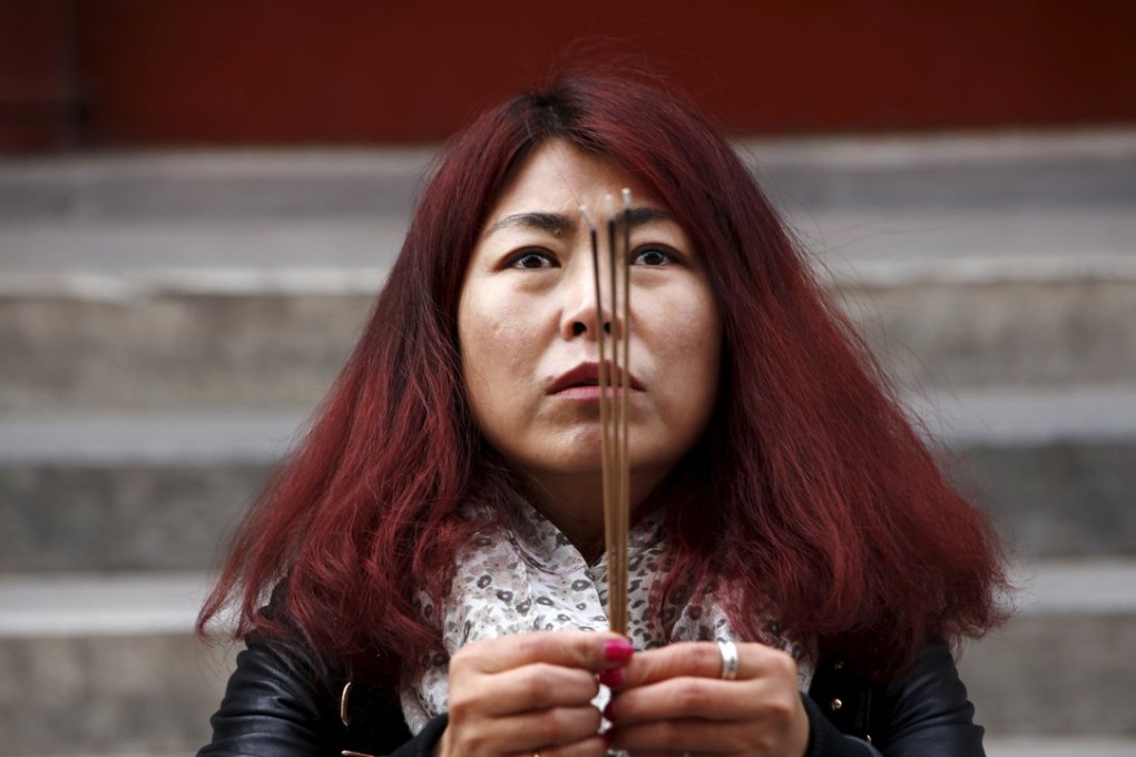 Cheng Liping prays at Lama Temple in Beijing on Tuesday for her husband, Ju Kun, who was on board Malaysia Airlines flight MH370, which went missing on March 8, 2014. Photo: Reuters