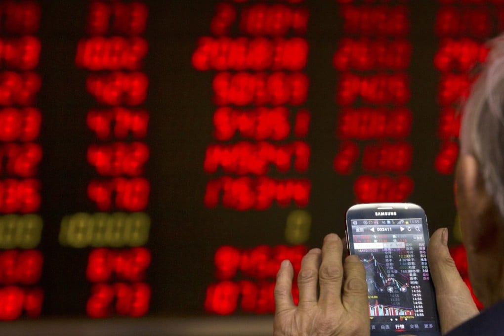 A Chinese investor in Beijing checks stock prices on his phone. Photo: AP