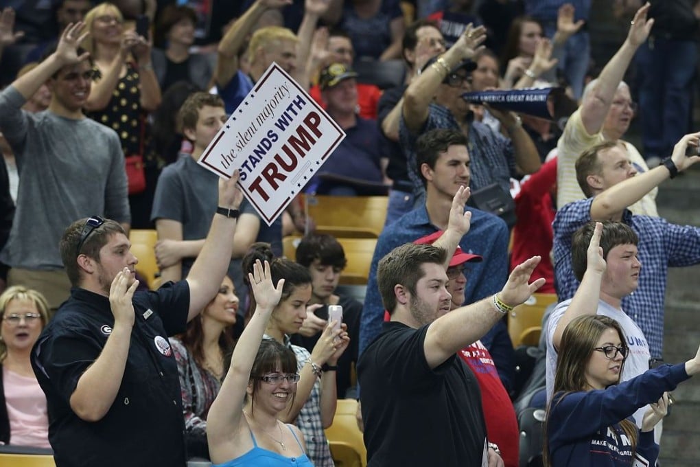 People raise their arms as Donald Trump has them pledge that they will vote for him during a campaign rally at the University of Central Florida in Orlando on Saturday. Photo: AFP