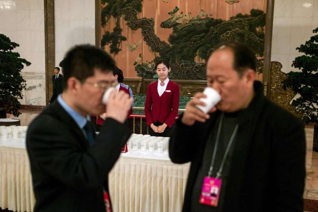 A hostess waits to serve guests as delegates drink tea during the opening ceremony of the National People's Congress in the Great Hall of the People in Beijing last Saturday. Photo: AFP