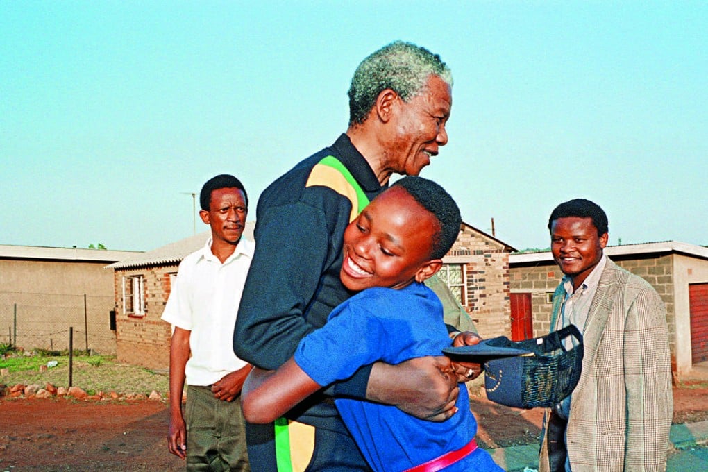 Anti-apartheid leader and later first black South African president Nelson Mandela hugs a young girl as he visits the black township of Soweto in 1990. Photo: AFP