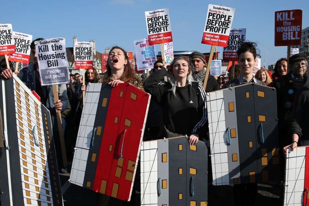 Protesters hold shields with housing tower blocks painted onto them as they stop on Westminster Bridge to chant slogans during a march through the streets of London on Sunday to demonstrate against the government’s housing bill. Photo: AFP
