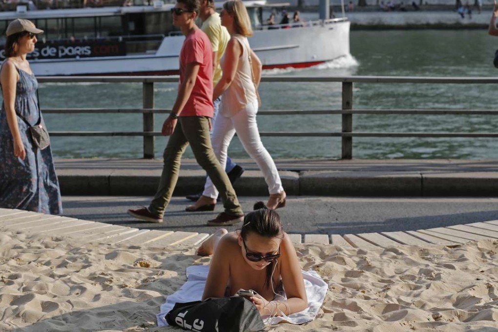 A sunbather enjoys the man-made beach next to Pont Neuf bridge along the River Seine in Paris. Photo: Reuters