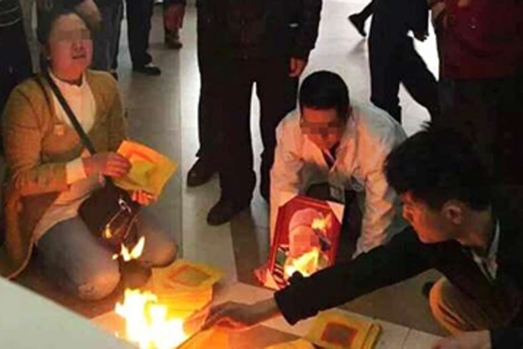 A doctor burns joss paper on Monday alongside the family and relatives of a dead child in the foyer of Shenzhen’s Pinghu People’s Hospital. Photo: SCMP Pictures