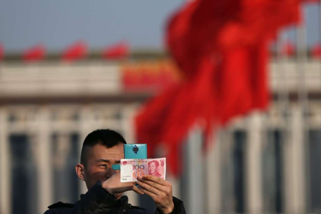 A man photographs a Chinese yuan note with his mobile phone in Tiananmen Square in Beijing on March 2. Photo: EPA