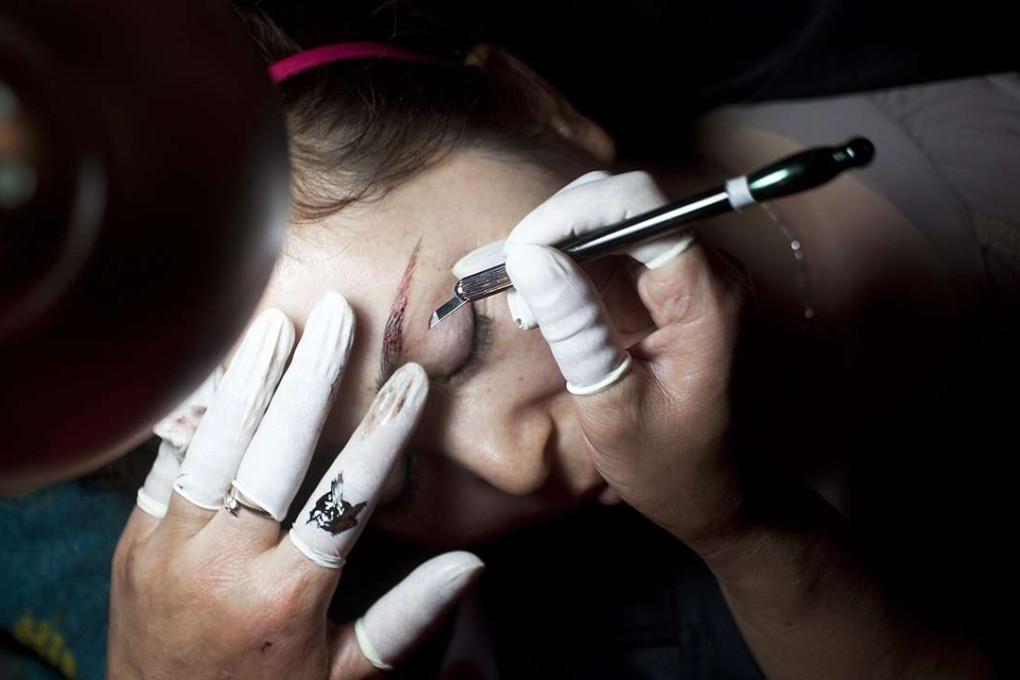 A woman has her eyebrows tattooed at a beauty, hairdressing and cosmetics expo in Beijing. Photo: EPA
