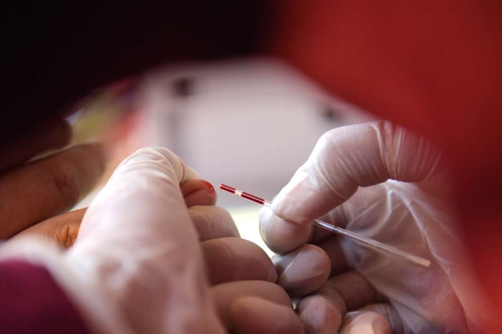 A Cambodian health worker takes a blood sample from a villager during an HIV screening drive in Kandal province. Photo: AFP