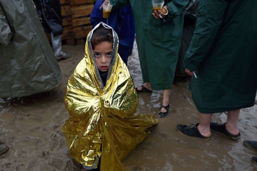 A child wrapped in a survival blanket waits in a queue for hot soup in a makeshift refugee camp on the Greek-Macedonian border. Photo: AFP