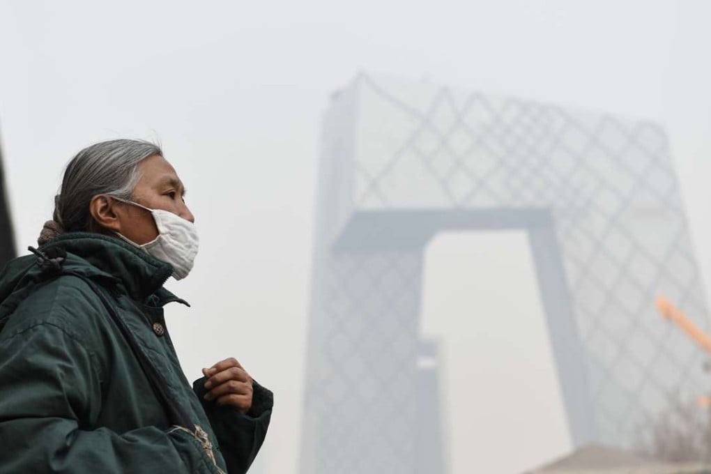 A woman wearing a mask walks past Guomao Bridge in Beijing, with the CCTV building behind her. Photo: Xinhua