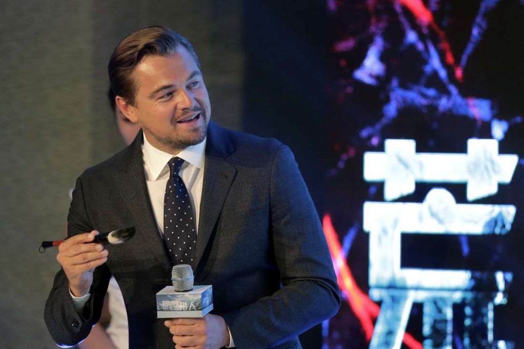 Leonardo DiCaprio holds a Chinese writing brush as he prepares to write his name during a news conference of the movie “The Revenant” in Beijing on Sunday. Photo: AP