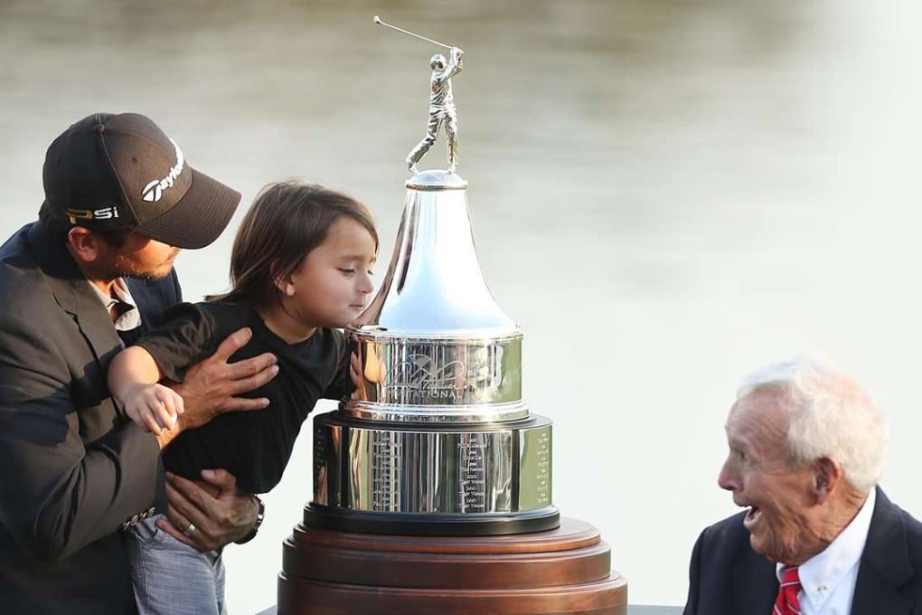 Arnold Palmer presents the winner’s trophy to Jason Day and his son Dash. Photo: AP