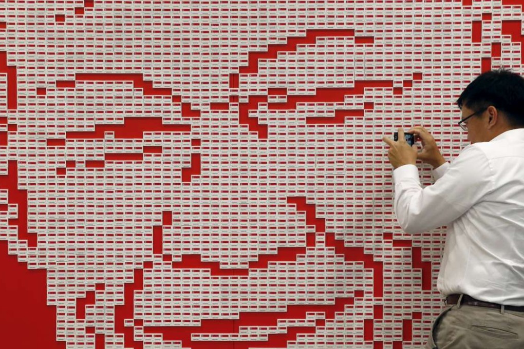 Shaun Lee, nephew of the late former prime minister Lee Kuan Yew, takes a photo of a portrait made up of 4877 rubbers that have the Singaporean flag printed on them. Photo: Reuters