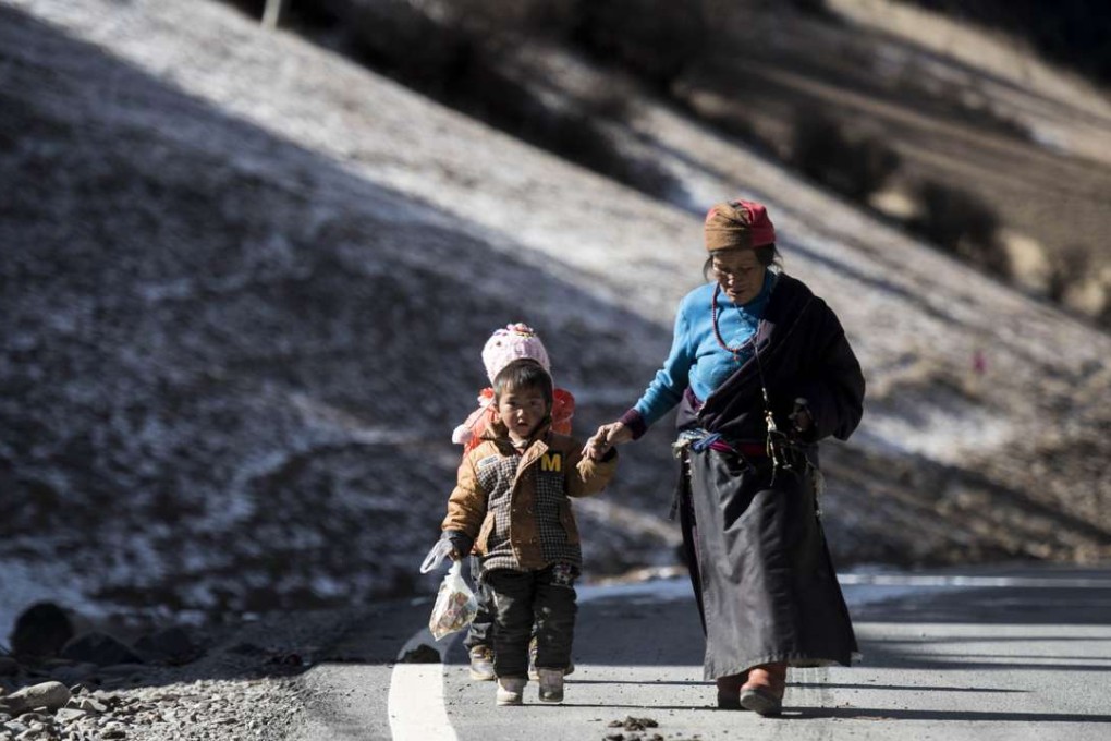 A woman and a child walk along a road in Dawu in the remote Garze Tibetan Autonomous Prefecture, Sichuan Province. Chinese authorities say urbanisation in Tibetan areas and elsewhere will increase industrialisation and economic development, offering former nomads higher living standards. Photo: AFP