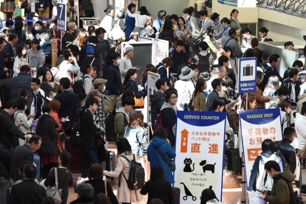 People wait in long queues to check in and get new reservations in front of counters for Japanese carrier All Nippon Airways (ANA) on the departures level of Haneda Airport in Tokyo on March 22, 2016. Photo: Kyodo