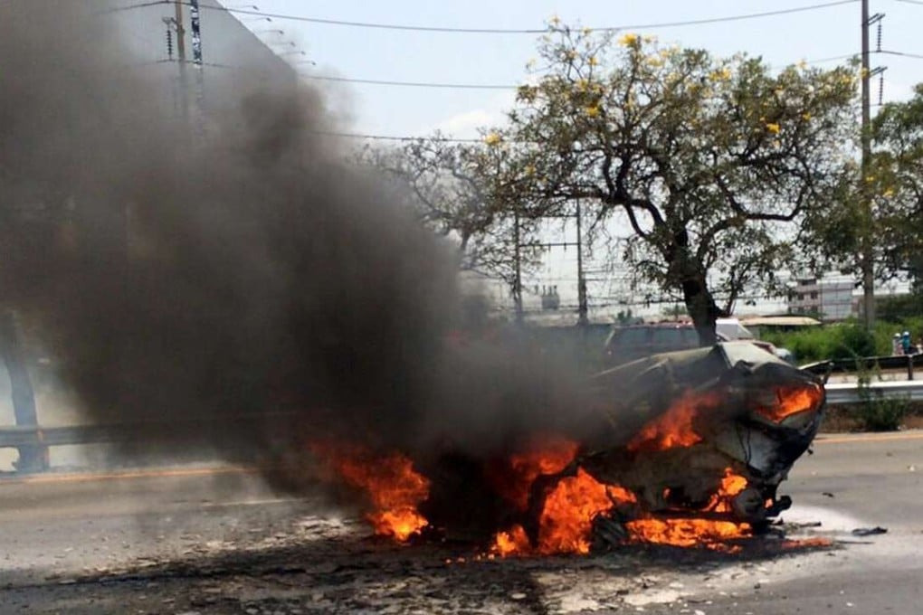 A Ford Fiesta burns after it was slammed into by a black Mercedes killing it's two occupants on a Thai highway. Photo: AP