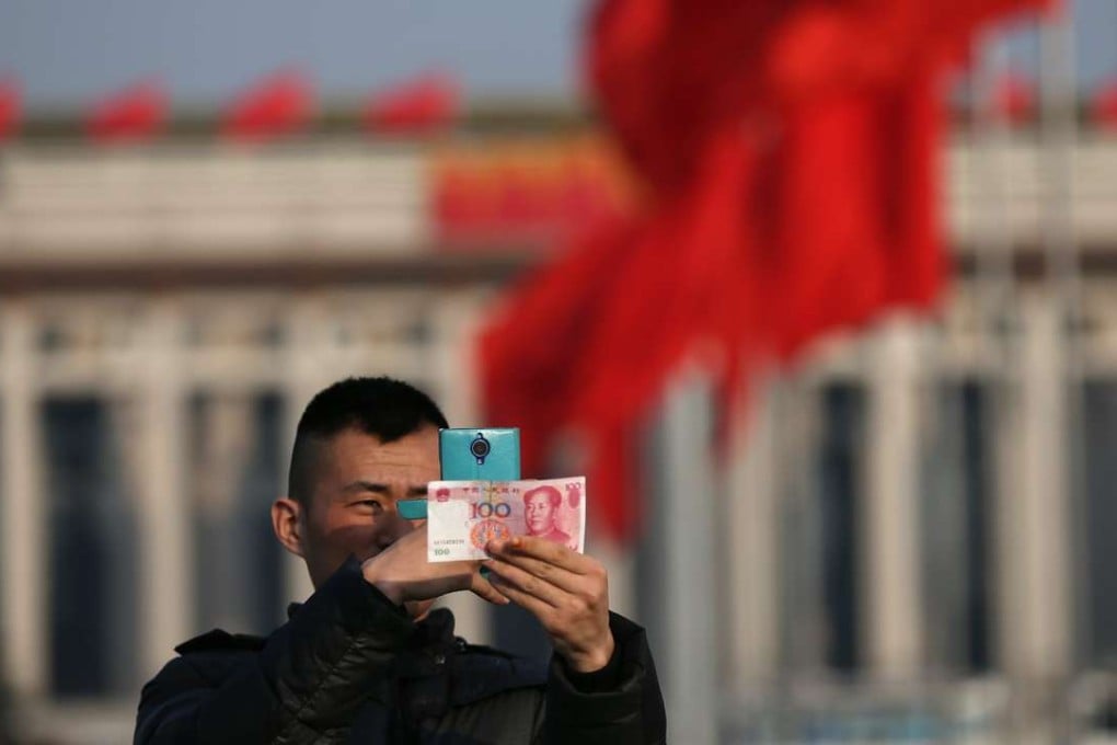 A man photographs a 100-yuan note in Tiananmen Square, Beijing. Photo: EPA