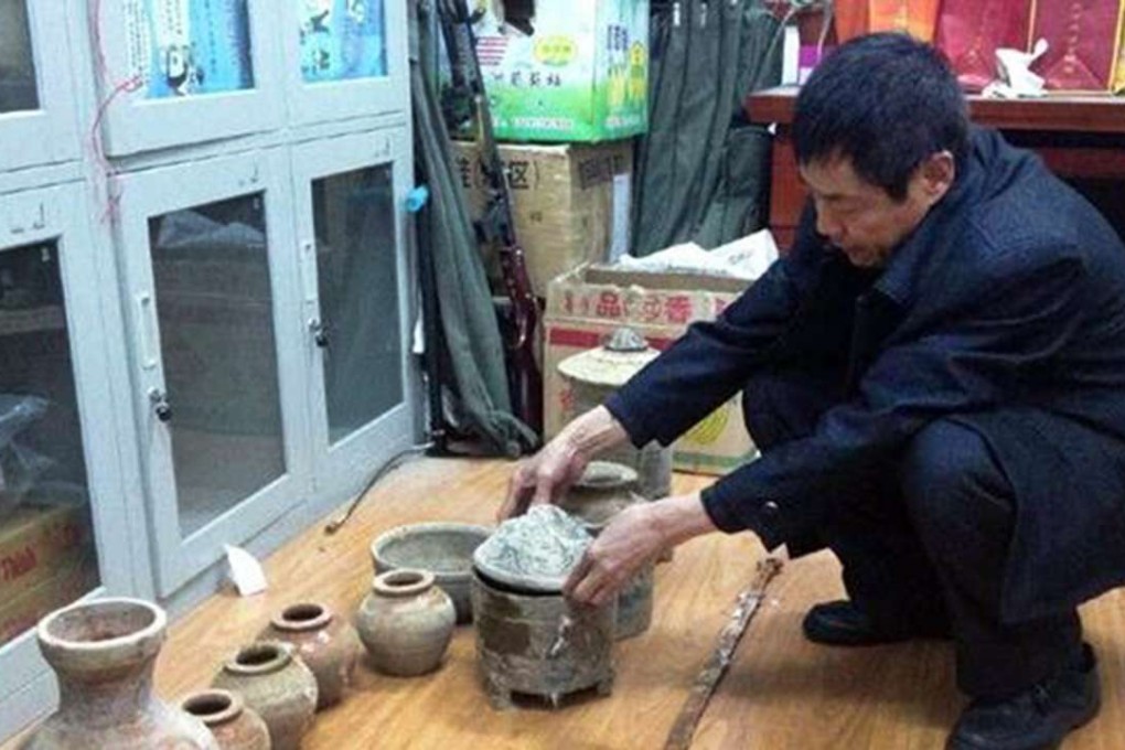 A man examines the confiscated artefacts that were dug up from an ancient Chinese tomb found in a backyard in Shaanxi province. Photo: China Business View
