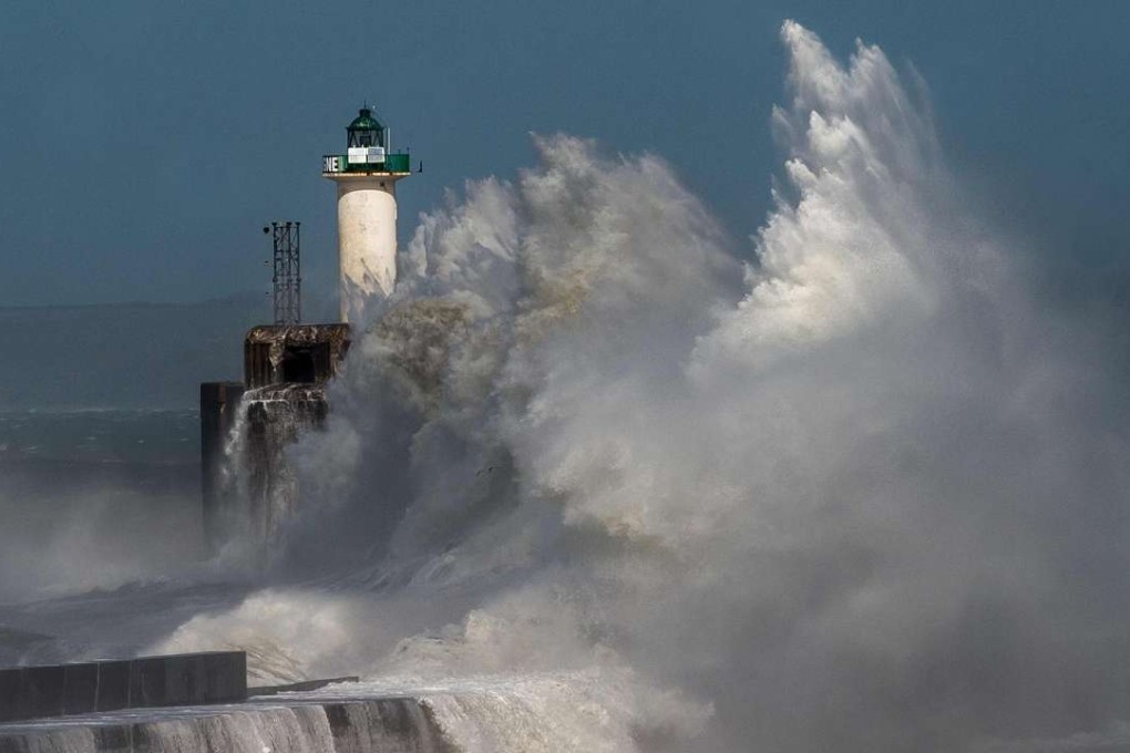 A wind-whipped wave breaks against a pier in front of a lighthouse in Boulogne-sur-Mer on Monday. Photo: AFP