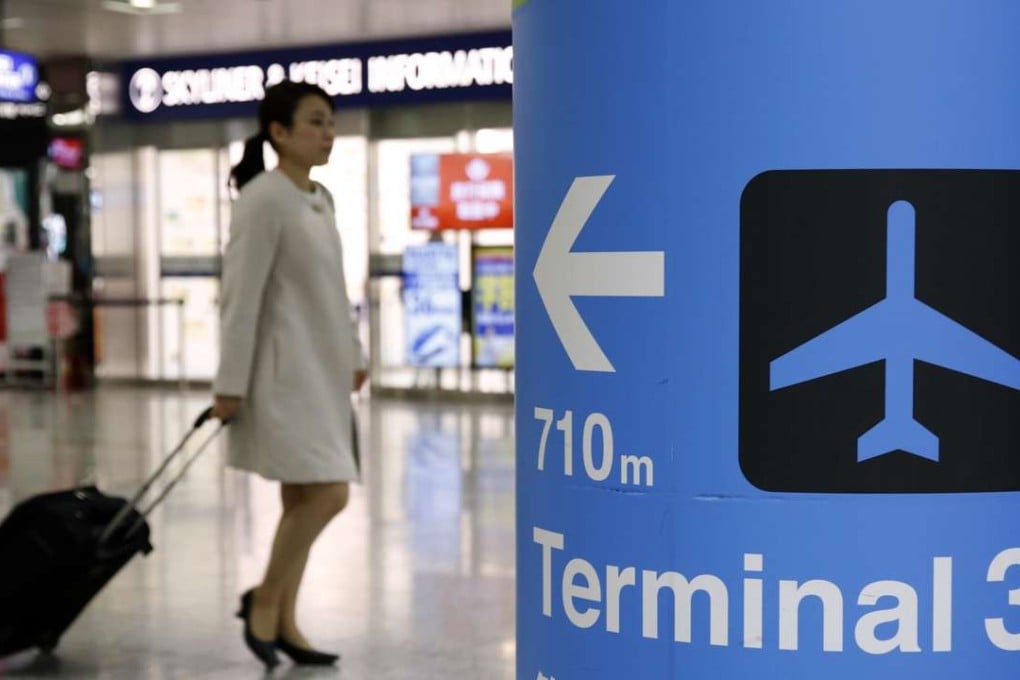 A woman is seen behind a sign directing to terminal 3 at Narita International airport near Tokyo. Photo: Reuters
