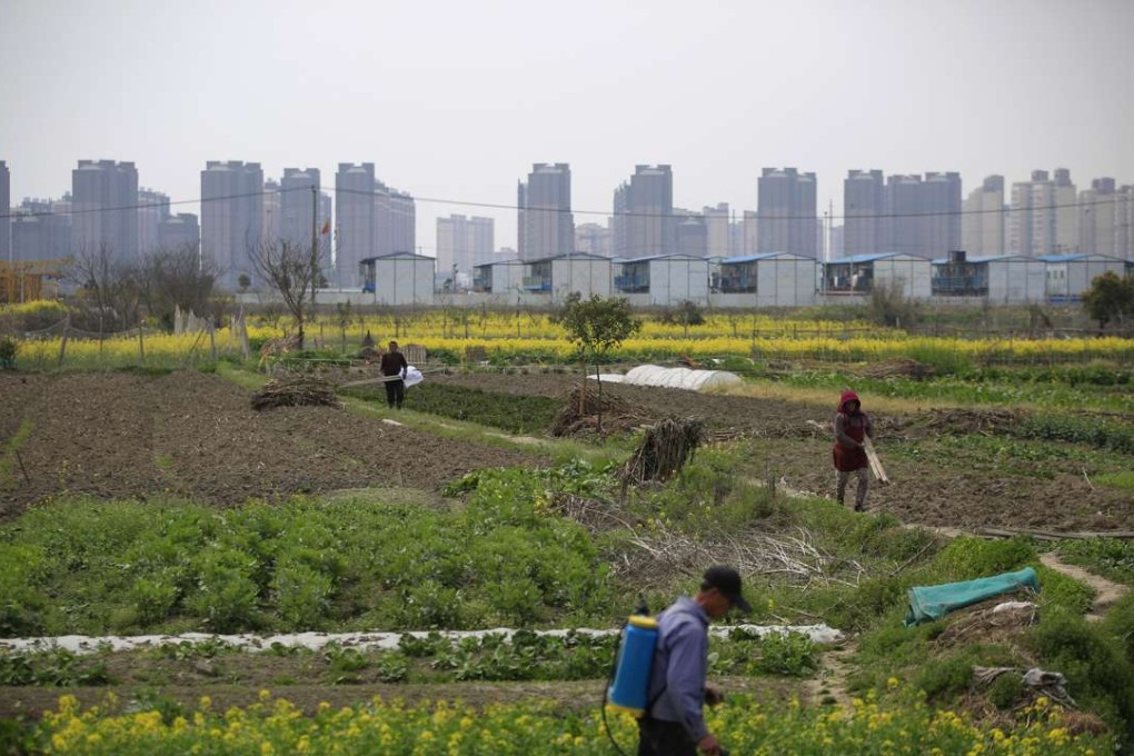 A farmer works on a farm in front of a construction site of new residential buildings in Shanghai on March 21, 2016. Photo: Reuters
