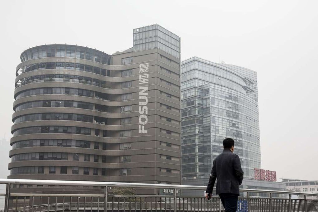 A pedestrian walks across a footbridge in front of the Fosun International Ltd. headquarters building in Shanghai. Photo: Bloomberg