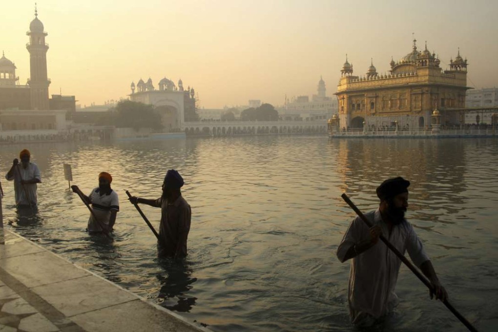 Indian Sikh devotees clean the tank early in the morning at the Golden Temple. Photo: AP