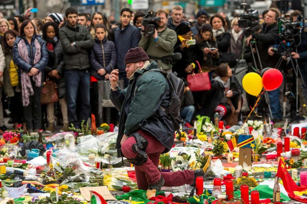 A man makes the sign of the cross during a minute of silence held at a makeshift memorial in front of the Brussels stock exchange on Place de la Bourse, two days after a triple bomb attack in the city. Photo: AFP