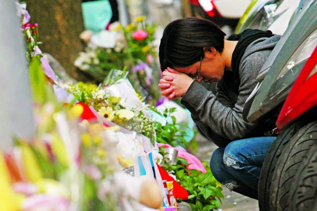 A woman prays in front of a makeshift memorial for a girl who was killed Monday by a knife-wielding assailant outside a subway station in Taipei, Taiwan. Photo: AP