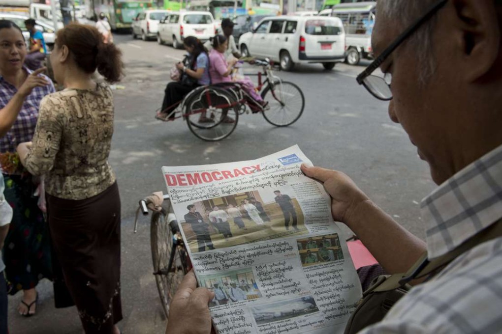 A Myanmar man reads a newspaper reporting on the handover of government in Yangon, a day before a new civilian government overseen by democracy icon Aung San Suu Kyi took office. Photo: AFP
