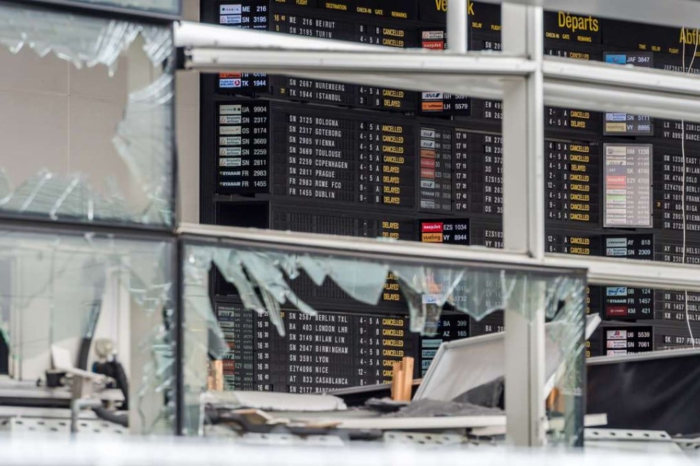 An arrivals and departure board is seen behind blown out windows at Zaventem Airport in Brussels. Photo: AP