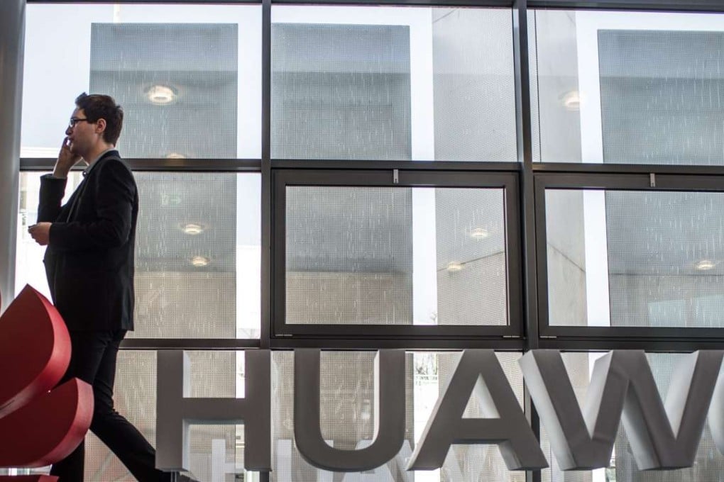 A man talks on his cell phone beside the logo of Huawei, the biggest technology equipment company in China, which is pursuing expansion through its partnereship with giants such as IBM. Photo: EPA