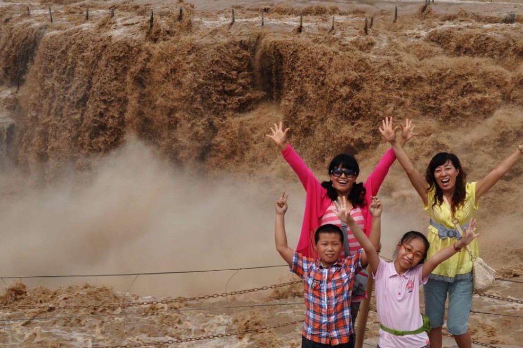 Tourists pose for photo at the Hukou Waterfall on the Yellow River in Shanxi province. Officials in two Chinese cities are trying to boost tourism by ordering government workers to take long weekends. Photo: Xinhua