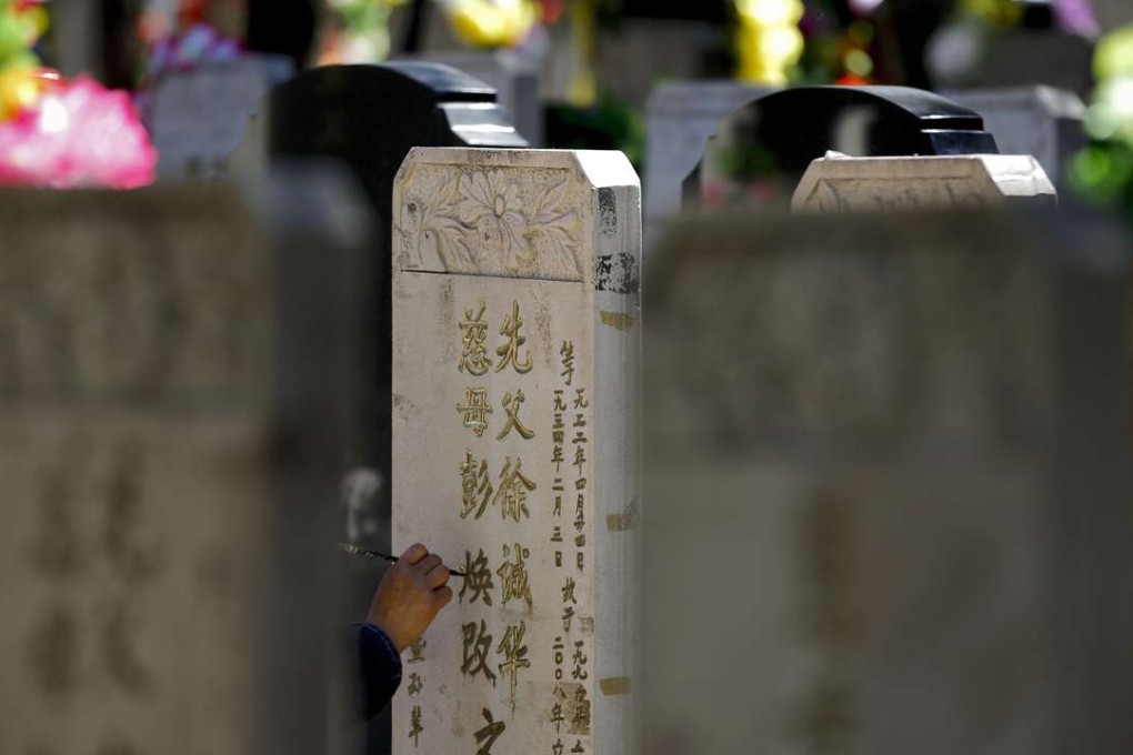 A woman repaints characters on the tomb stone of her deceased relatives at the Babaoshan on Sunday. Photo: AP