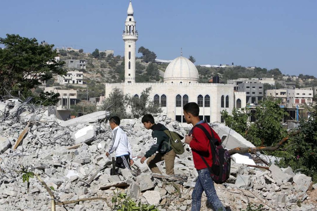 Boys walk amongst the rubble of the house of Palestinian assailant Ahmed Najeh Abu al-Rub after it was demolished by Israeli forces in the West Bank town of Qabatya near Jenin on April 4, 2016. Photo: Reuters