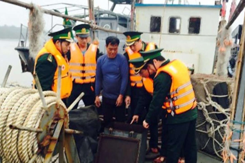 The captain of a Chinese vessel, in blue, is surrounded by members of the Haiphong Coast Guard after they boarded his refuelling boat last Thursday. Photo: Hai Phong Coast Guard/ Thanh Nien