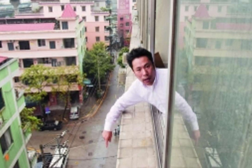 The boy’s father stands beside the upstairs window of a building in Guangzhou from where his son reportedly leapt to his death. Photo: Information Times