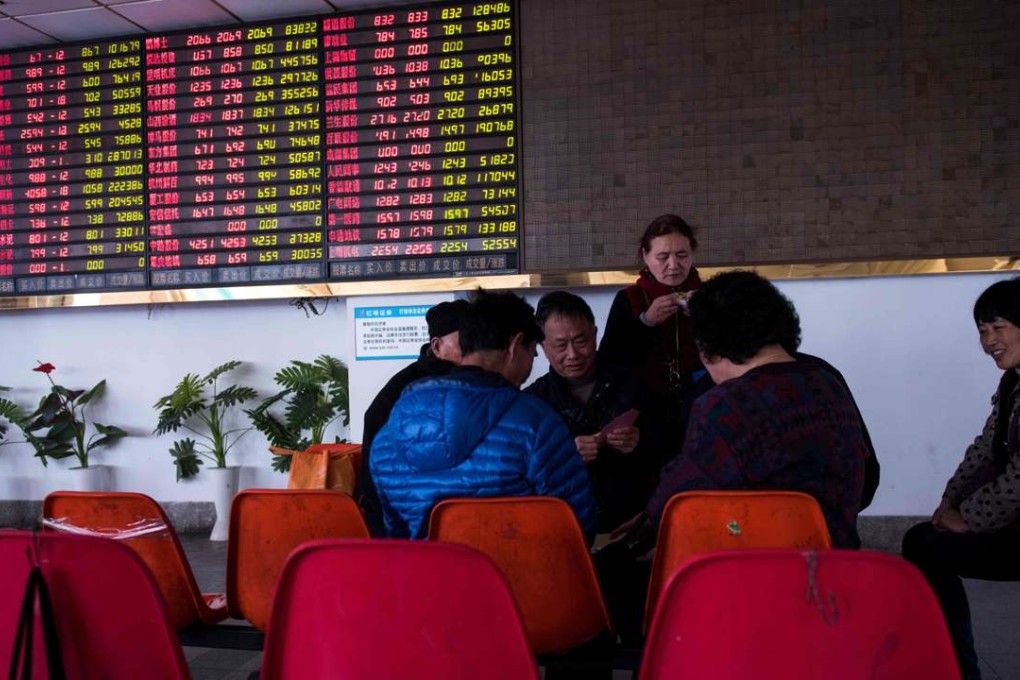 Investors play cards next to an electric board showing stock market movements at a securities brokerage in Shanghai. Photo: AFP
