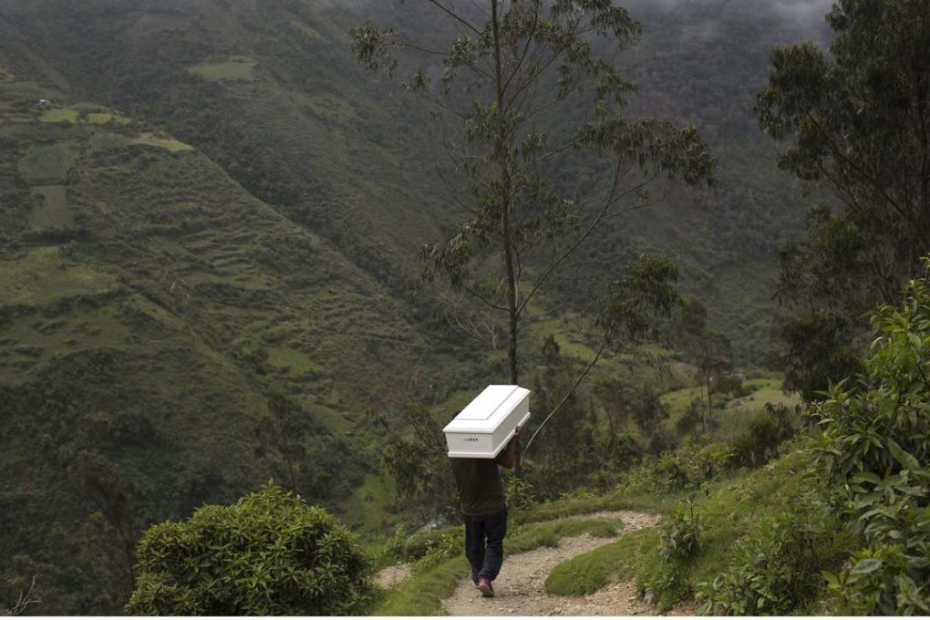 A man shoulders a coffin with the remains of a loved one who was slain more than two decades ago by Shining Path rebels, as he walks to the cemetery for a group burial service in Ccano, a village in the Huanta area of Peru, last month. Photo: AP