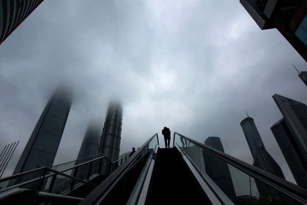 A man rides an escalator in front of high-rise buildings in Shanghai’s Lujiazui financial district. Photo: AFP