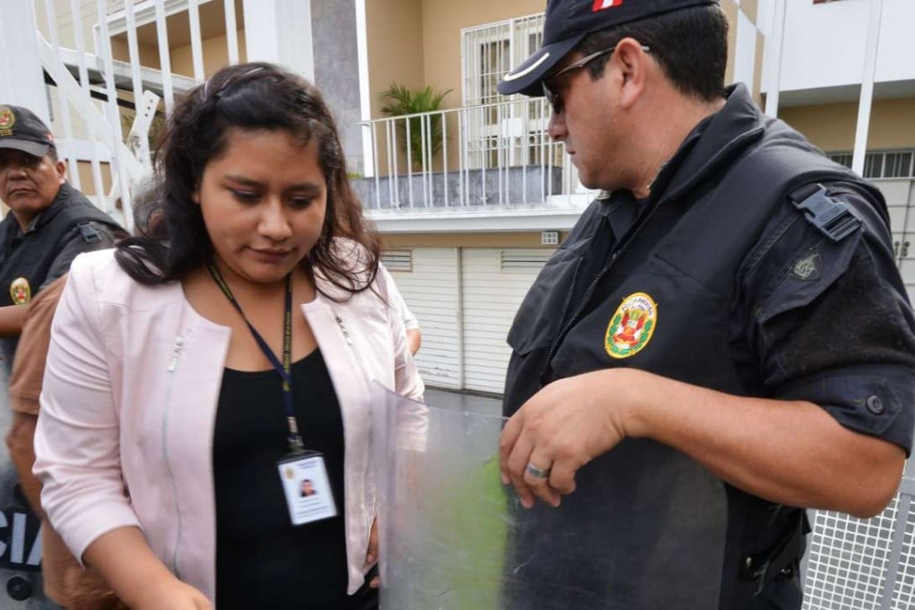An investigator exits the Mossack Fonseca offices in Lima, Peru, watched by police, during a raid on Monday. The office is located directly across the road from the Panamanian embassy. Photo: AFP