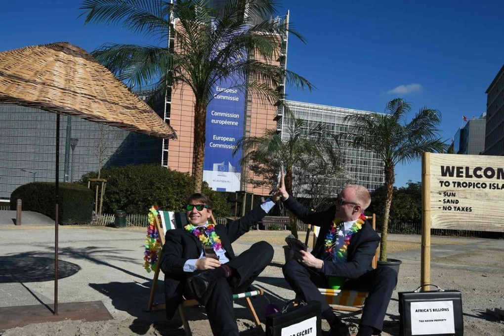 Activists perform as clients of an offshore company during a protest of non-governmental organisations Oxfam and Transparency International in front of the European Commission headquarters in Brussels, on April 12, 2016. Photo AFP