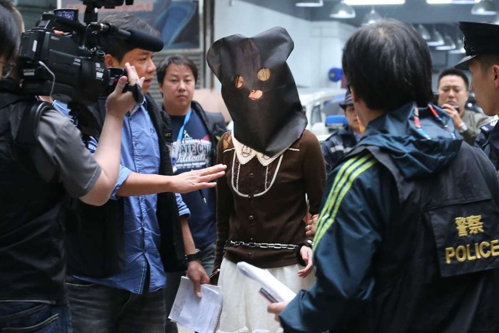 The suspect was hooded and handcuffed when she got out of an unmarked police car and was escorted into the building at 3.10pm. Photo: Felix Wong