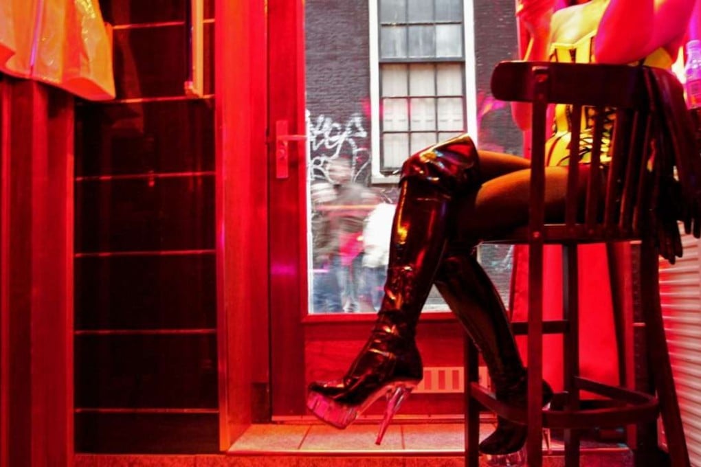 A prostitute waits for clients behind her window in the red light district of Amsterdam. Photo: AFP