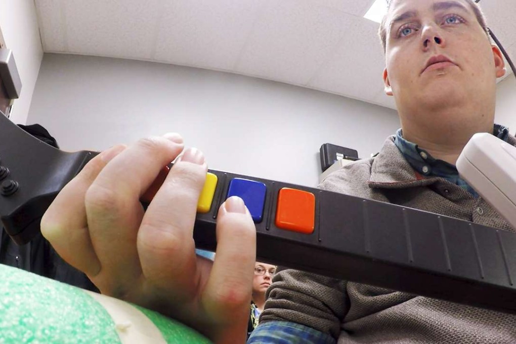 Ian Burkhart, 24, plays a guitar video game as part of a study with neural bypass technology in this undated handout picture released by Ohio State University Wexner Medical Centre in Columbus, Ohio. Photo: Reuters