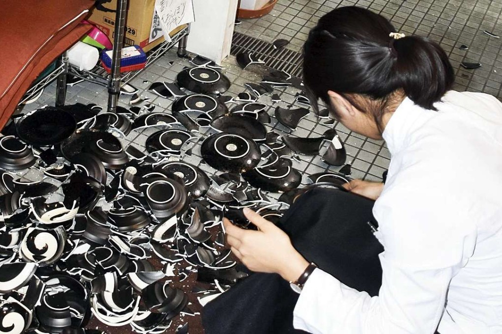 A woman collects fallen dishes at a restaurant after an earthquake in Kumamoto, southern Japan, April 14, 2016. Photo: Kyodo