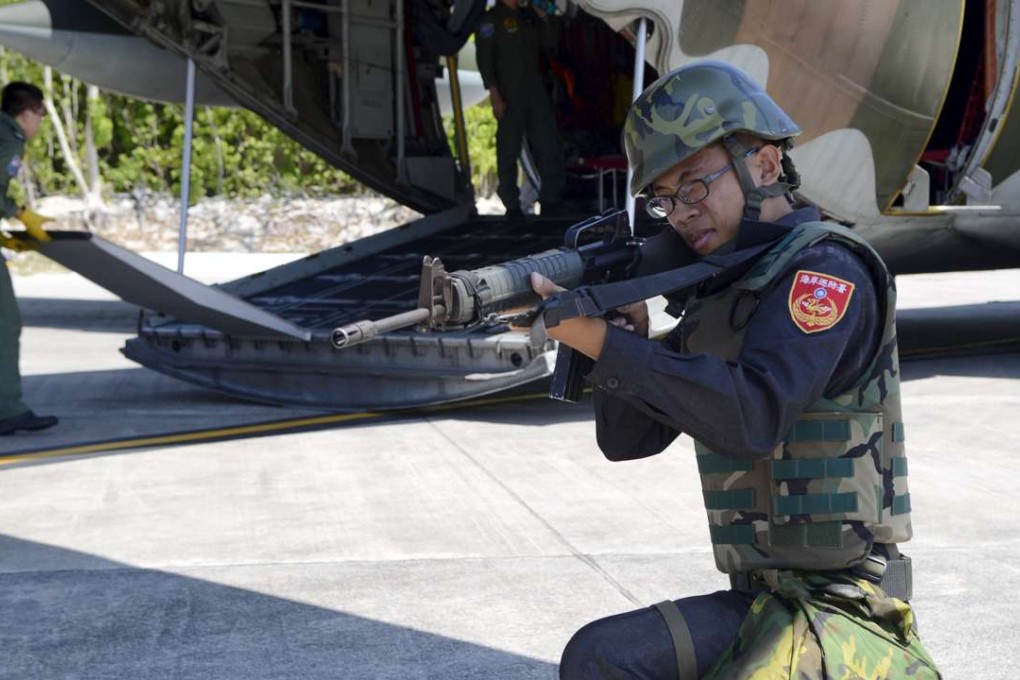 A Taiwanese coast guard secures a C-130 military transport plane on the tarmac, in Itu Aba, which the Taiwanese call Taiping, on the South China Sea. Photo: REUTERS, Fabian Hamacher